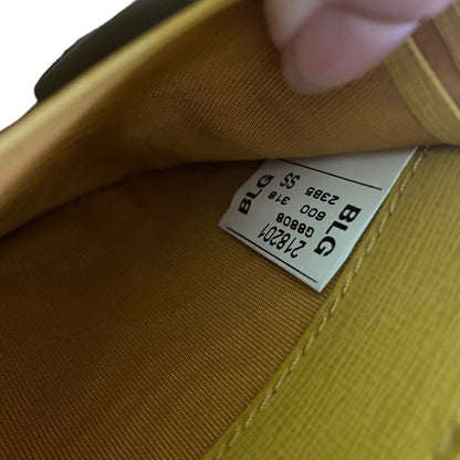 Close-up of the interior lining of a yellow wallet, showing a sewn-on size and model label .