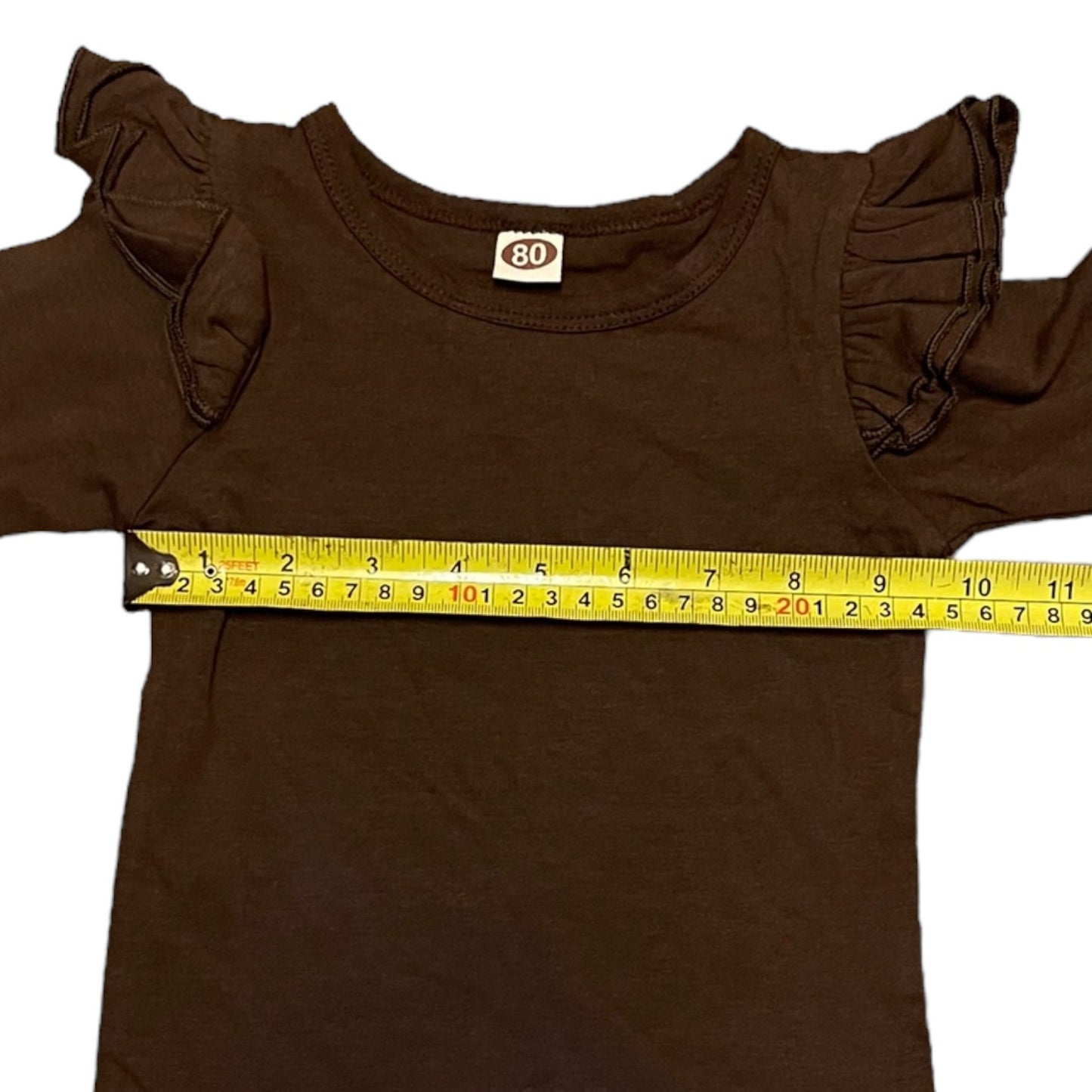 Brown baby shirt with ruffled sleeves and a measuring tape indicating size 80 on a white background