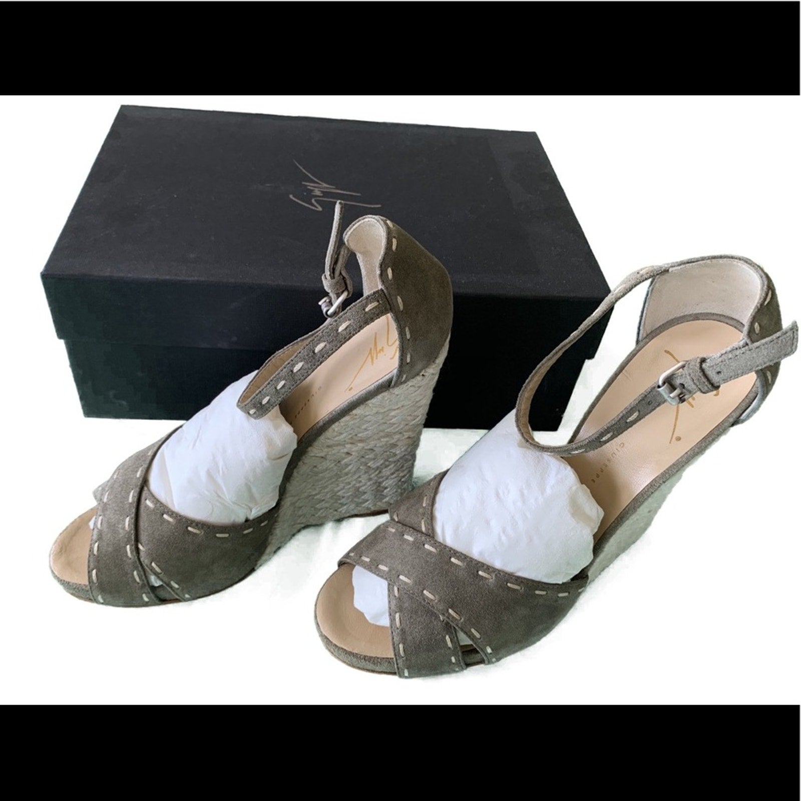 Pair of green wedge sandals with white soles on a white background and black box
