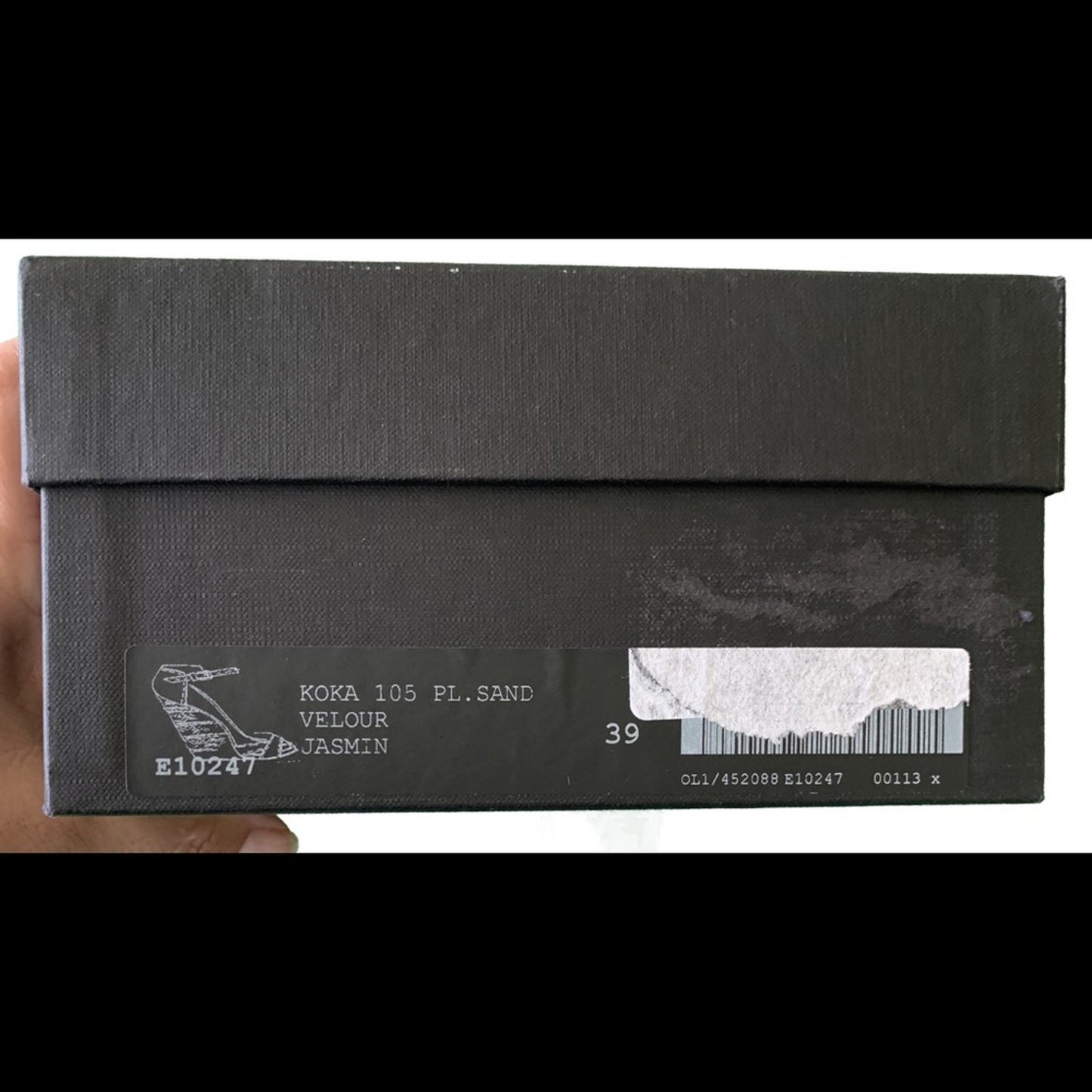 Black shoe box with text and a barcode held by a hand