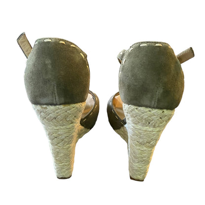 Pair of wedge sandals with textured sole and green suede upper on a white background