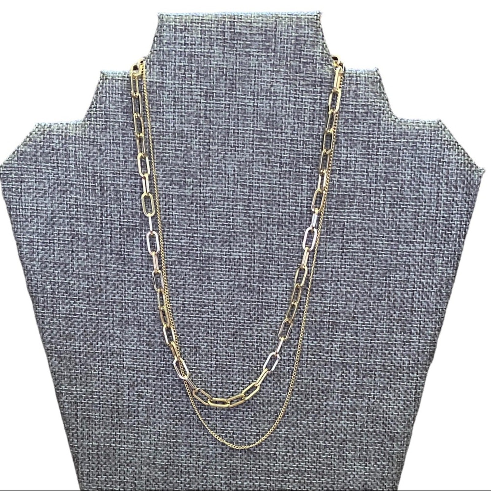Gold chain necklace on a gray bust display