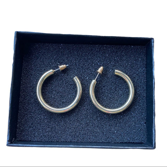 A pair of polished gold-tone hoop earrings displayed inside an open  presentation box with a dark blue  insert.
