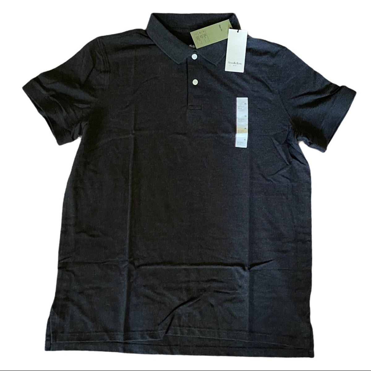 A gray short-sleeve polo shirt with a two-button placket, laid flat on a white background with retail tags attached.