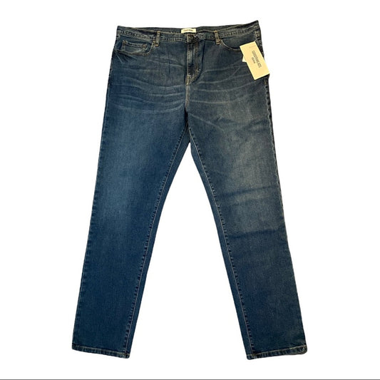 A pair of medium wash blue denim jeans with a yellow paper tag attached to the waistband, displayed flat against a plain white background.