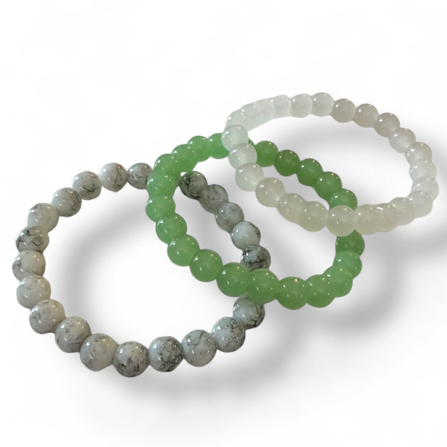 Three beaded bracelets in different colors on a white background