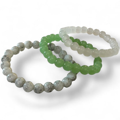 Three beaded bracelets in gray, green, and white on a white background