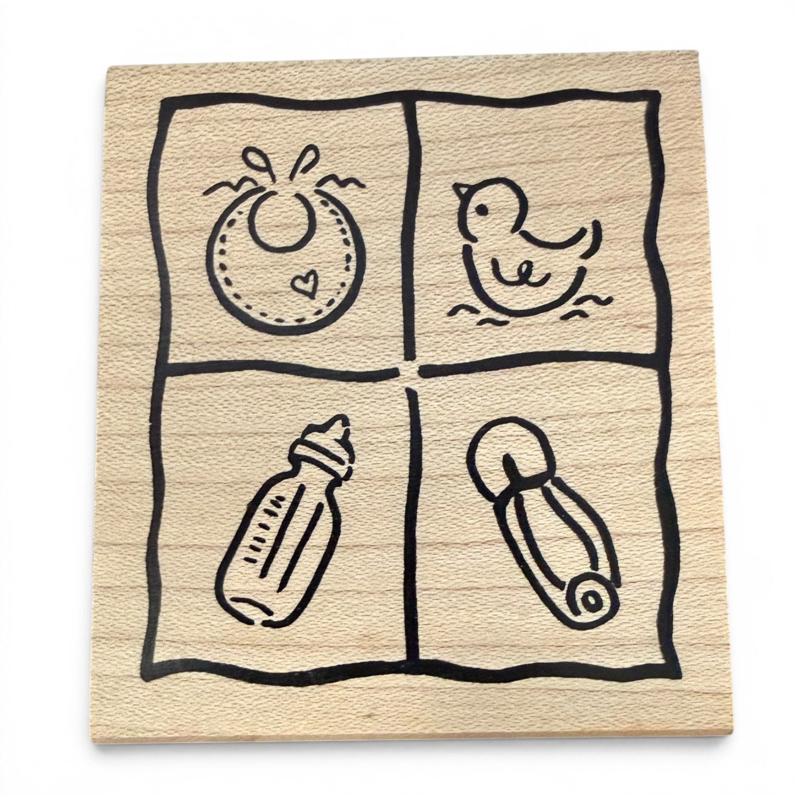 Wooden baby-themed stamp with illustrations of a bottle, diaper, and other items on a white background.