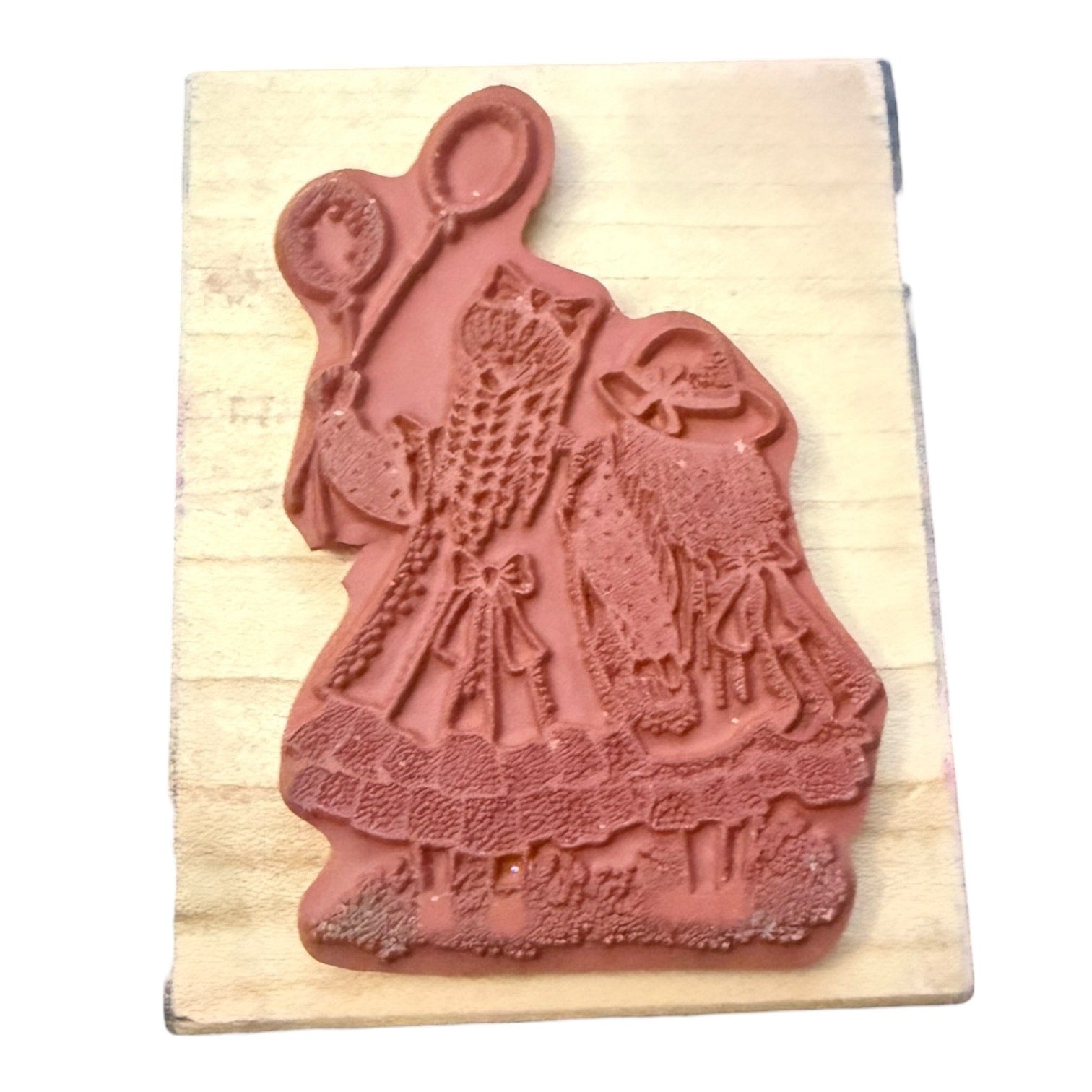 Decorative rubber stamp with a design of a woman holding balloons on a wooden block.