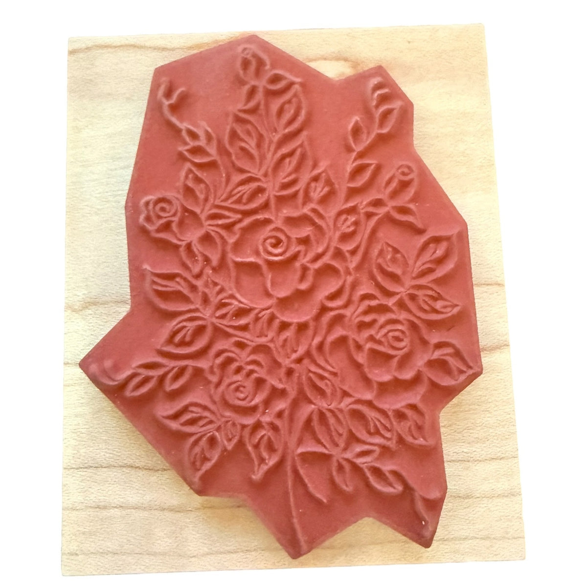 Rose and vine rubber stamp on a wood block on a white background. 