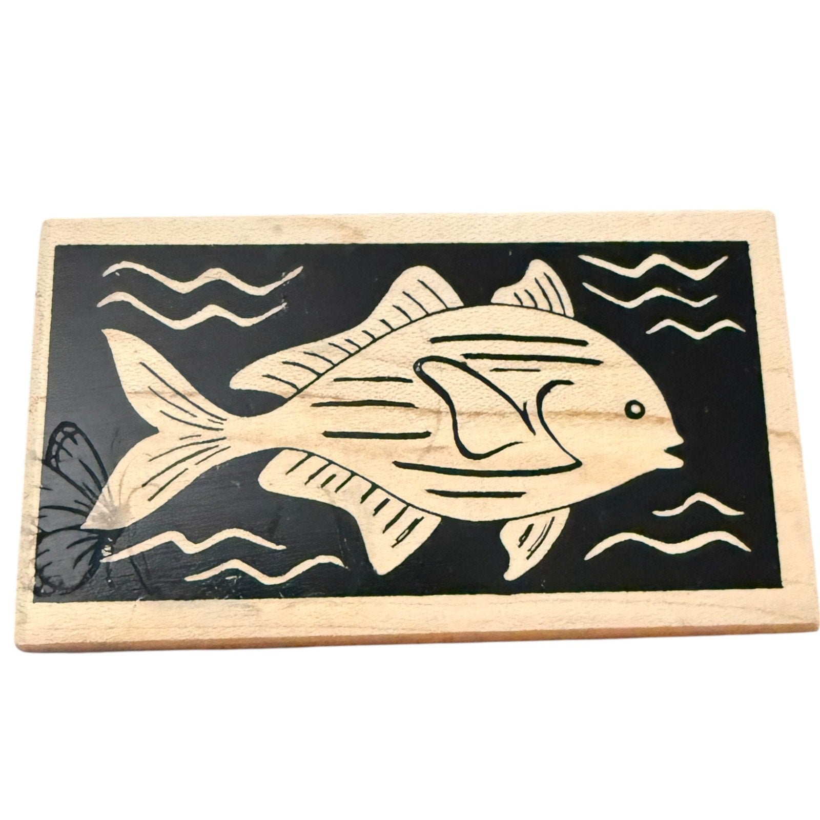 Wooden stamp with a fish design on a black background