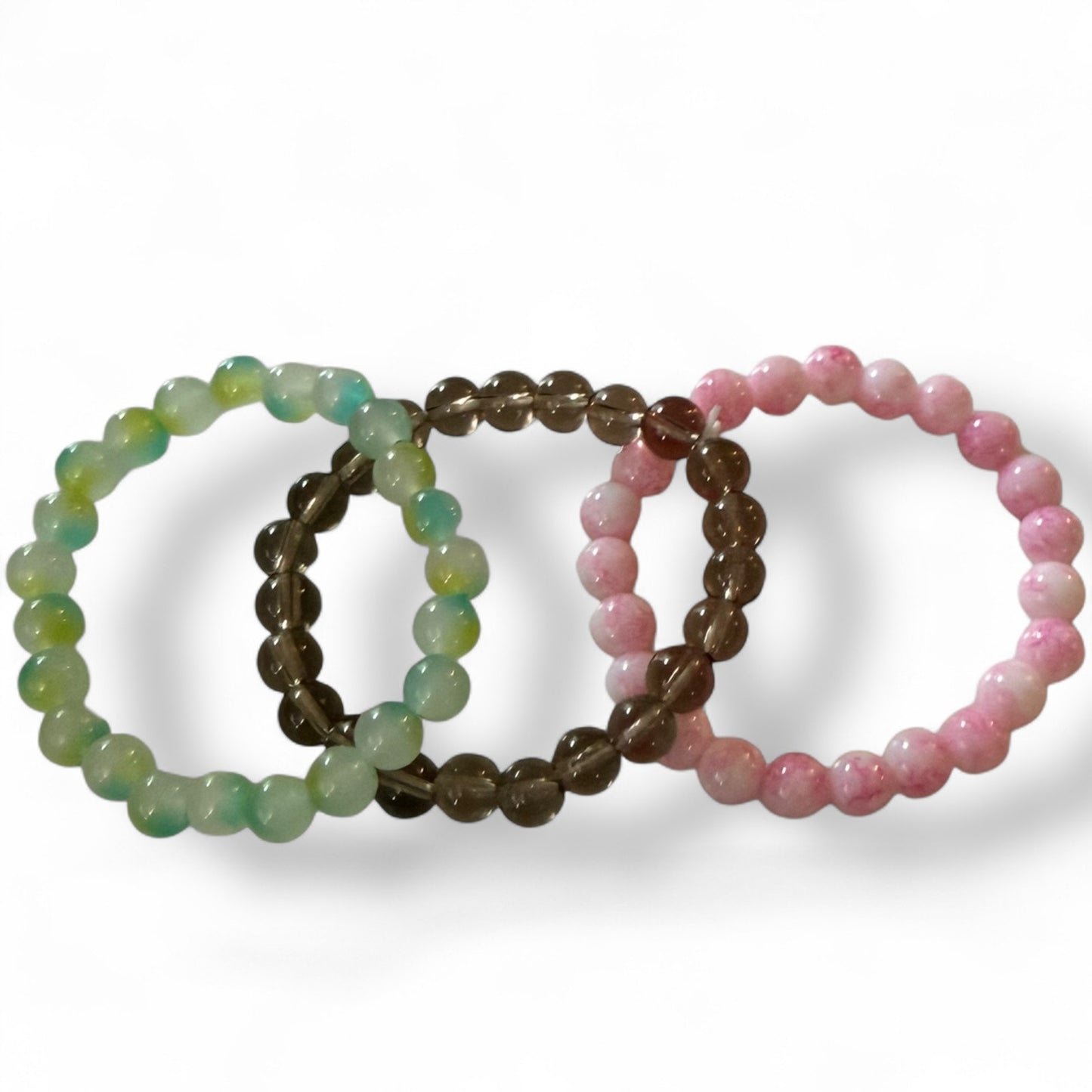 Three beaded bracelets in green, smoke, and pink on a white background