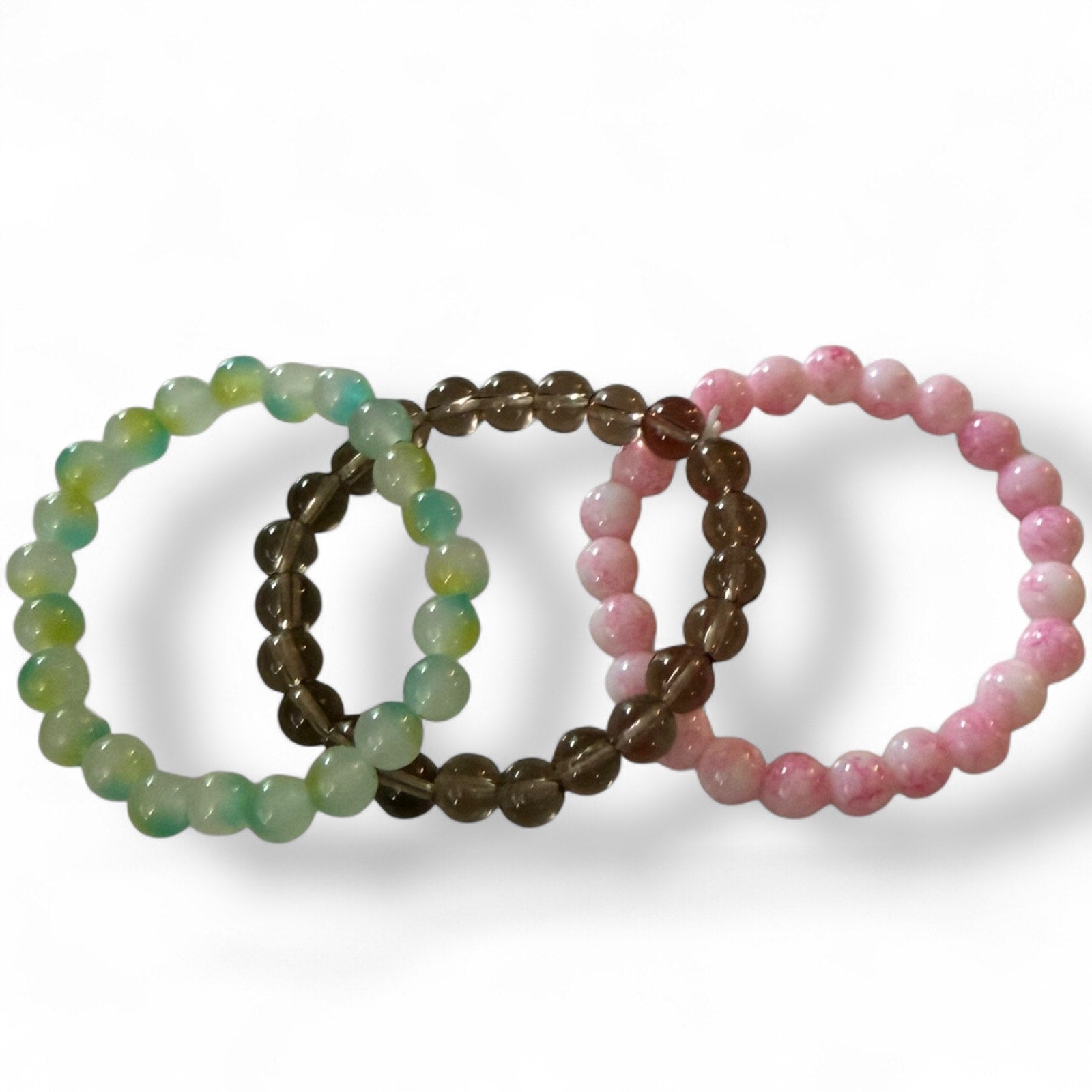 Three beaded bracelets in green, smoke, and pink on a white background