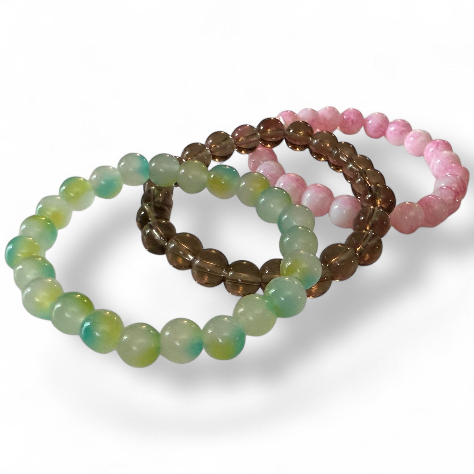 Set of three beaded bracelets in green, smoke, and pink on a white background