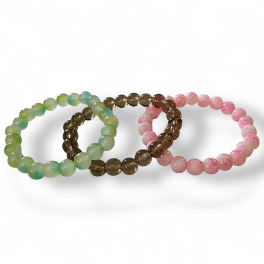 Three beaded bracelets in green, smoke, and pink on a white background