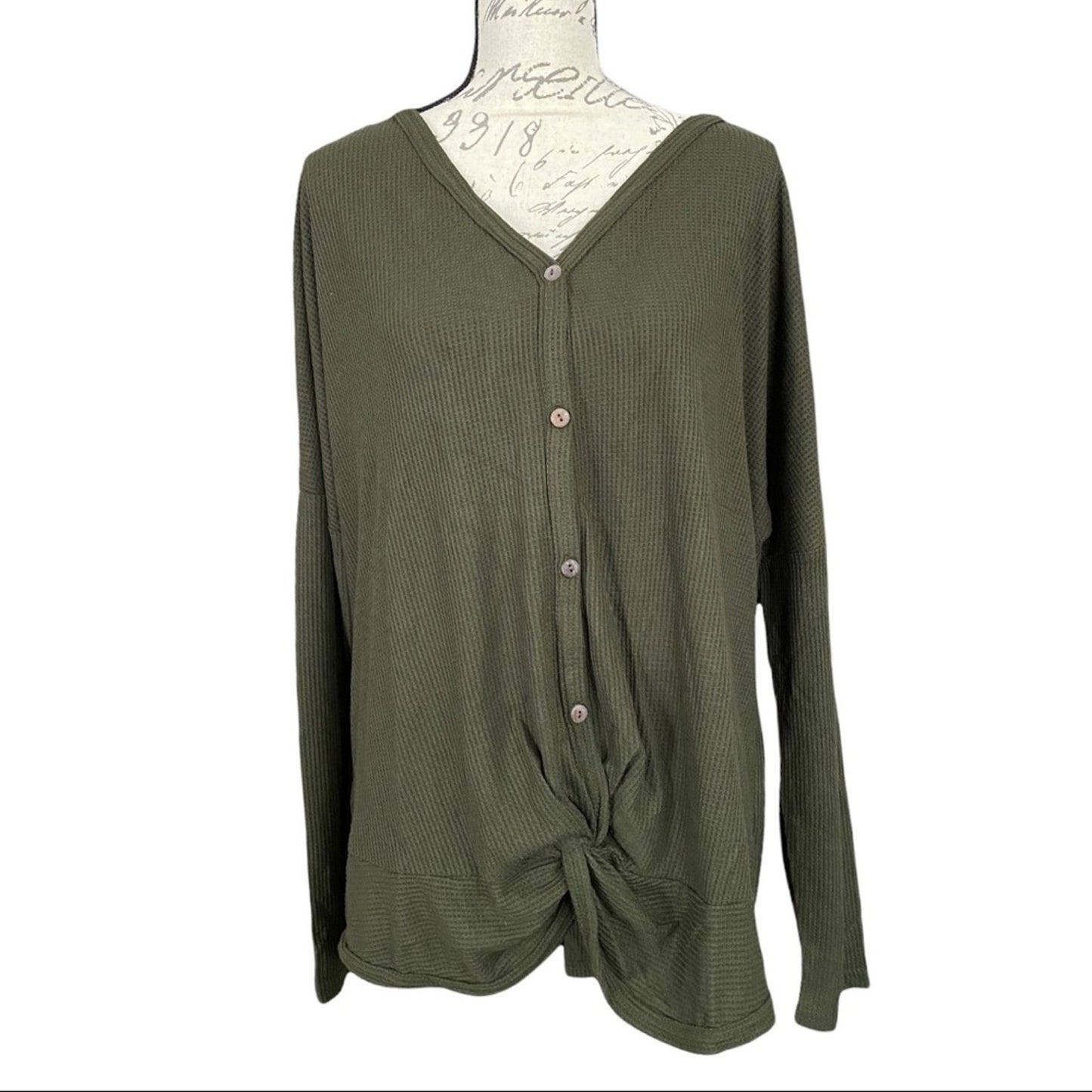 Front of green shirt on a mannequin against a white background
