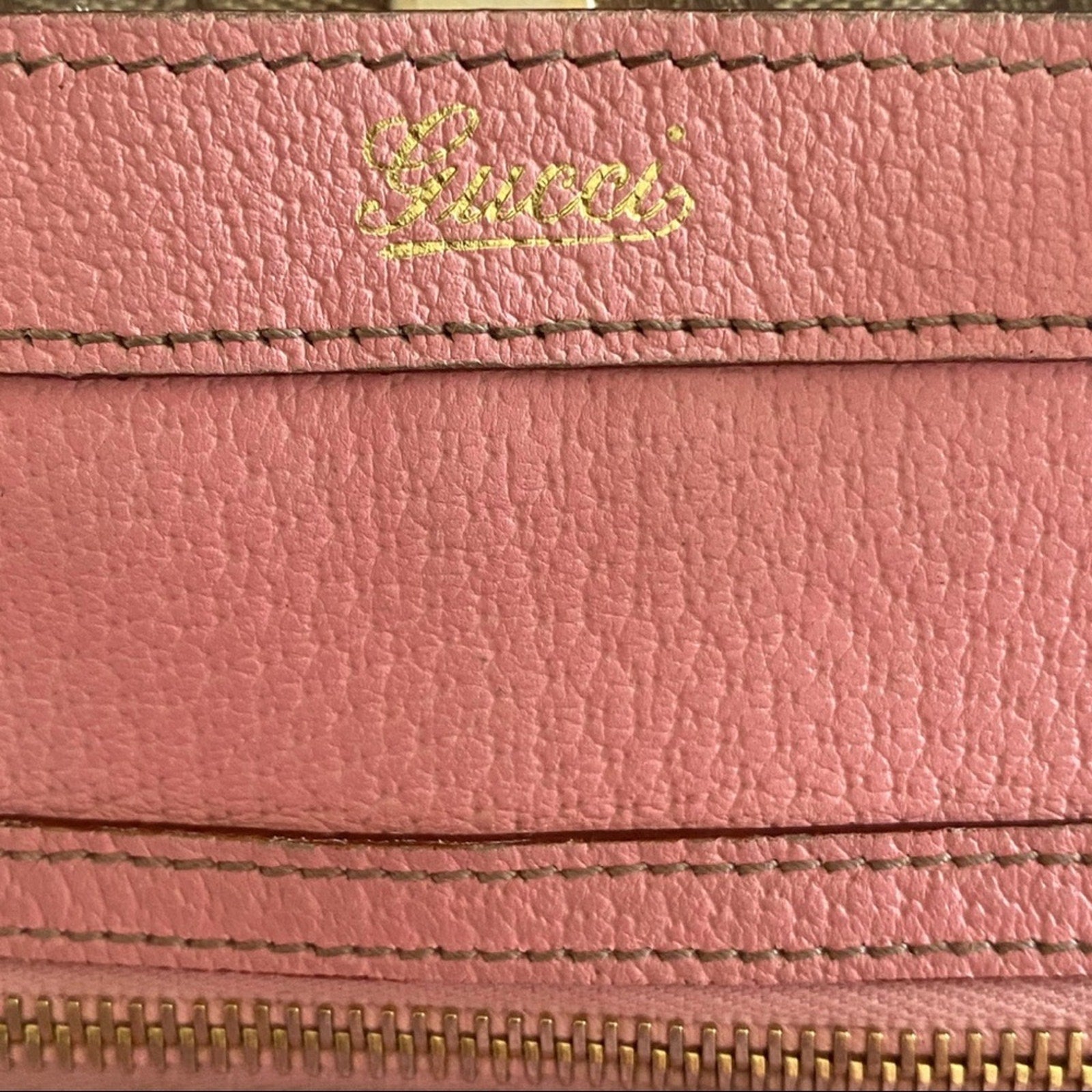 Close-up of a pink leather purse with 'Gucci' branding.