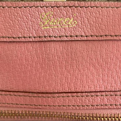 Close-up of a pink leather purse with 'Gucci' branding.