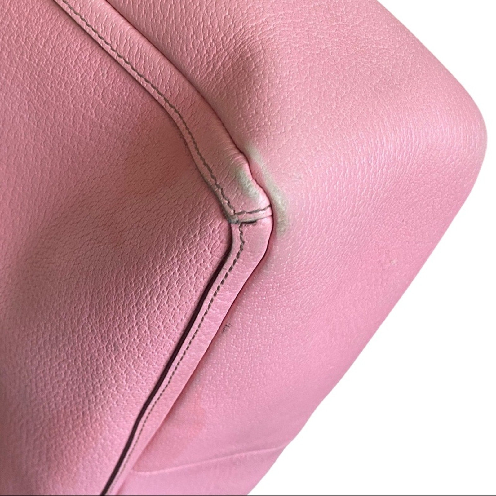 Close-up of corners on pink leather with visible stitching on a white background