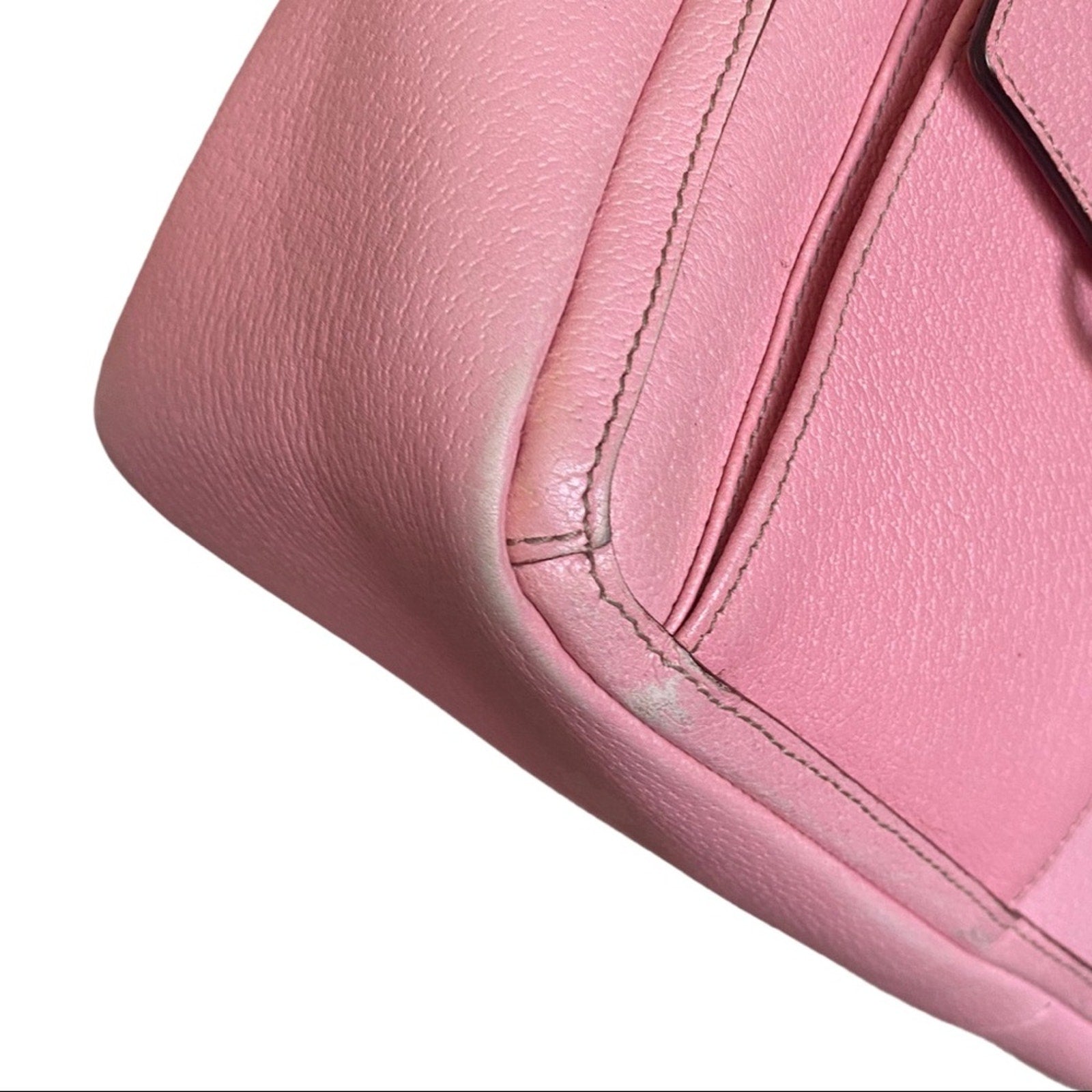 Close-up of corners of pink leather purse with visible stitching on a white background