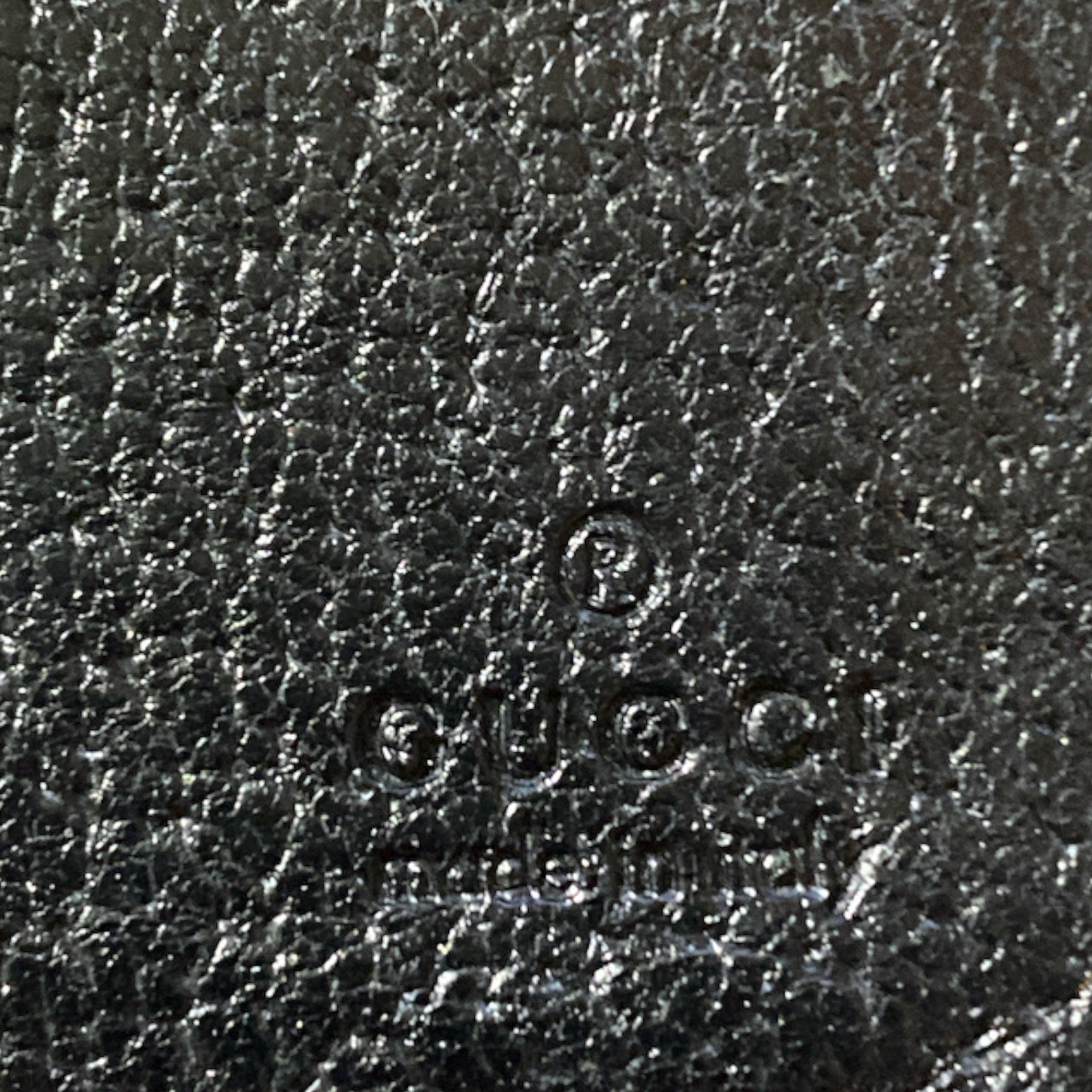 Close-up of Gucci logo on black leather texture