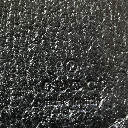 Close-up of Gucci logo on black leather texture