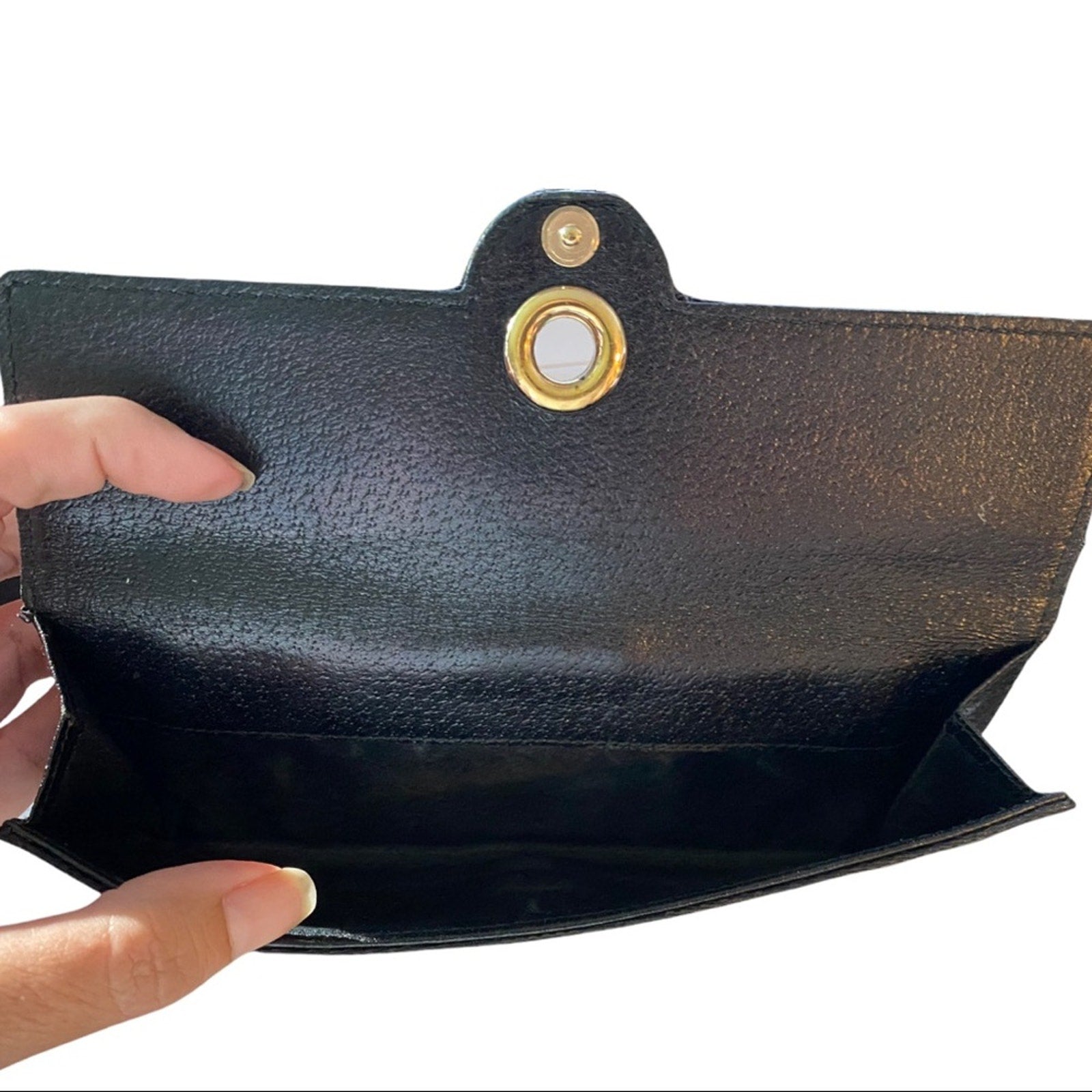 Interior of coin pocket on black Gucci wallet held by a hand on a white background
