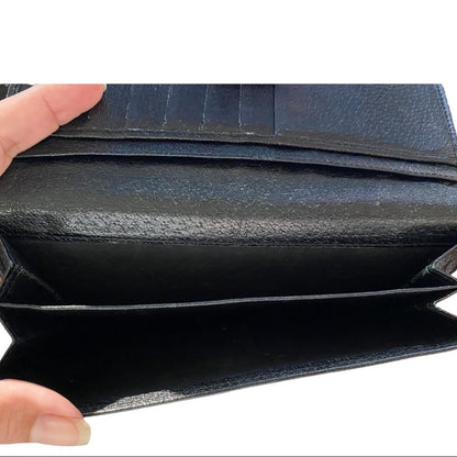Black leather wallet interior pockets held open by a hand on a white background