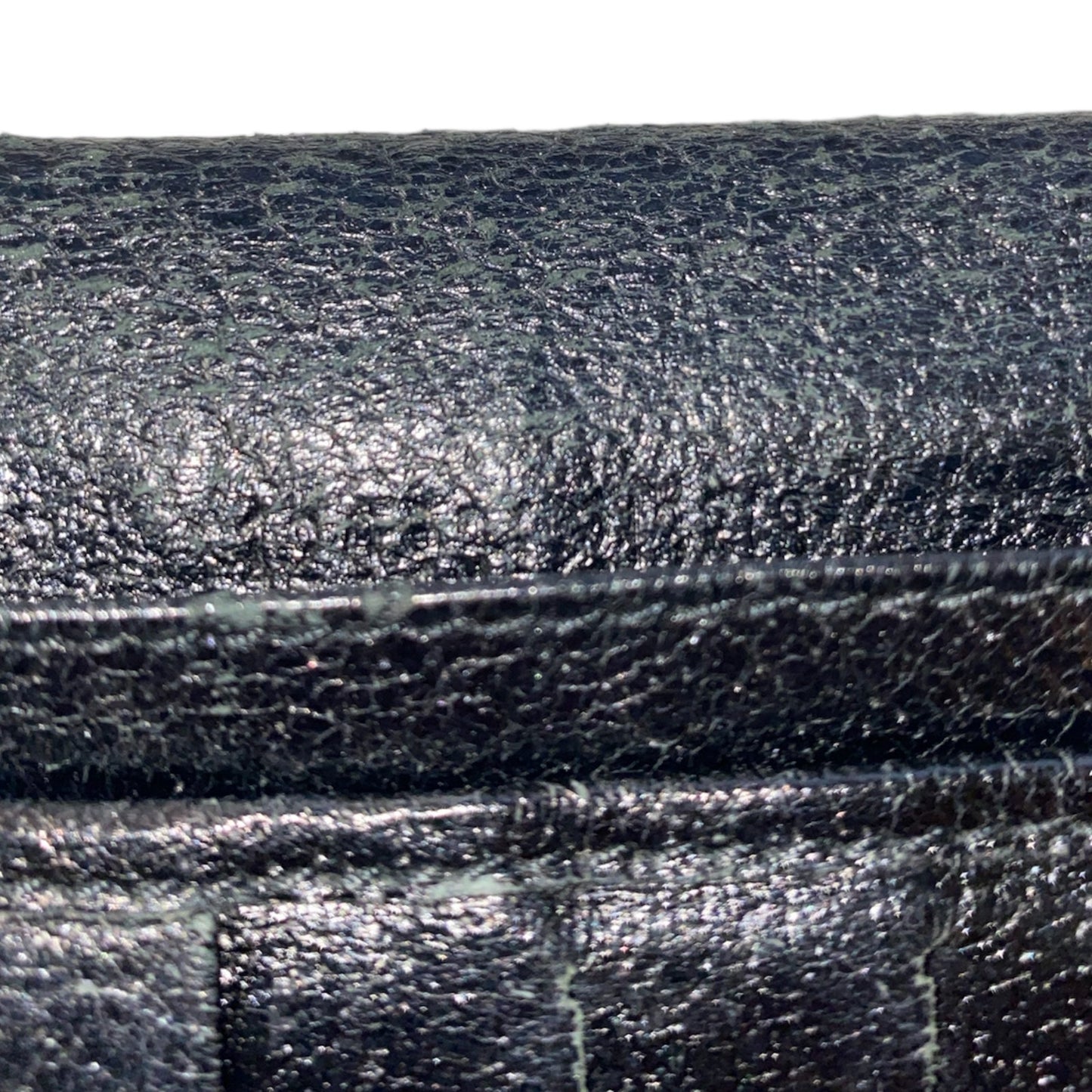 Close-up of black leather serial number on Gucci wallet