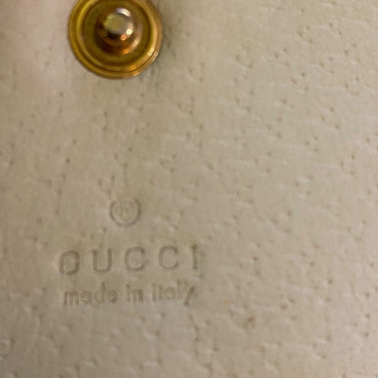 Close-up of Gucci logo on a beige textured surface with a gold circular detail.