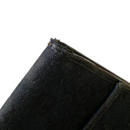 Close-up of a black corner of wallet with visible frayed edges and black stitching against a plain white background.