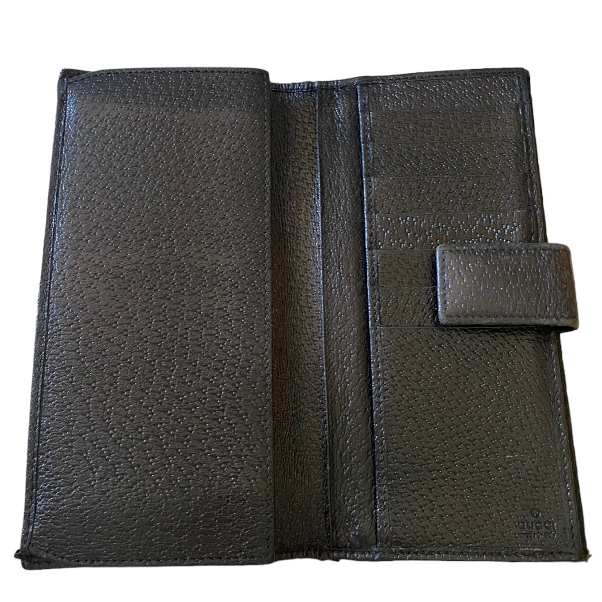 Interior of a black textured leather wallet shown open against a plain white background, displaying its interior compartments and a small tab closure on the right side.