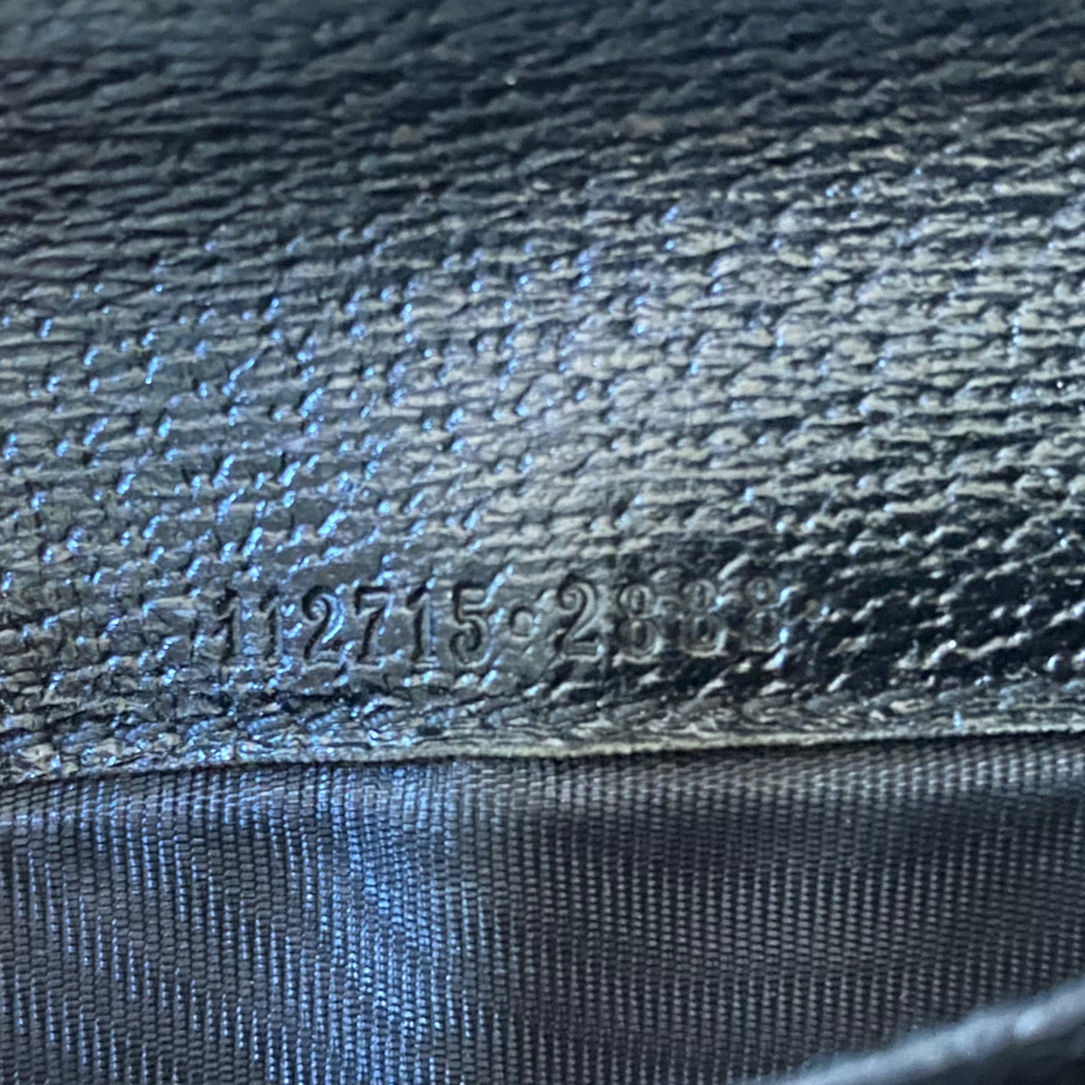 Close-up of a dark textured leather surface with embossed numbers and a darker woven fabric band below.