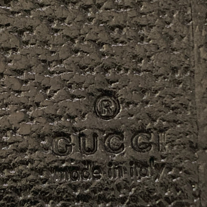 Close-up of textured black leather with an embossed GUCCI logo and 'made in italy' on the surface.