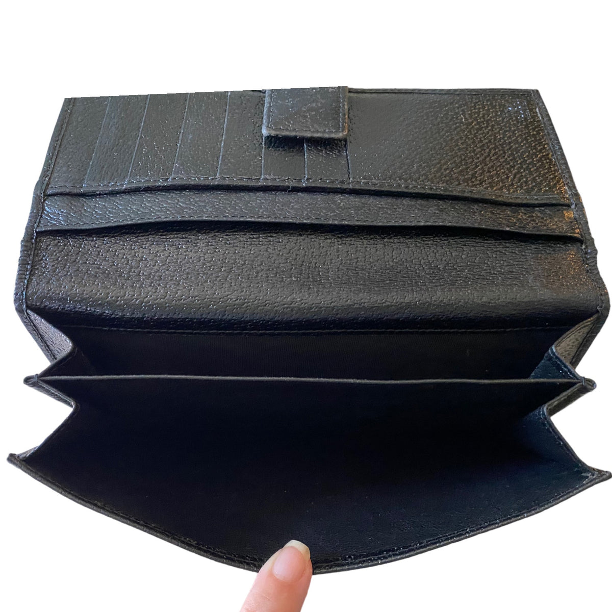 A black textured leather wallet shown open, revealing multiple card slots and interior compartments, with a finger holding the bottom edge against a plain white background.