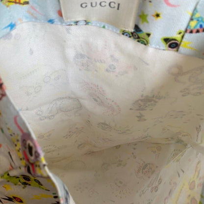 Close-up of a Gucci bag interior showing  lining , alongside a colorful patterned exterior fabric and a visible Gucci brand label.