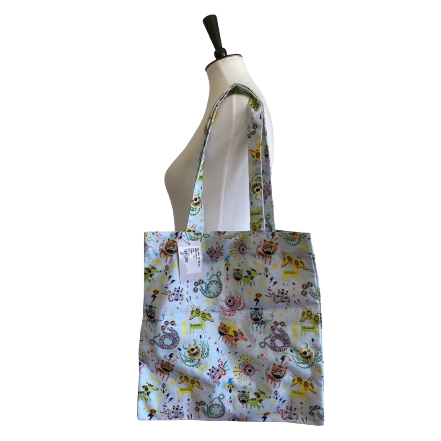 Blue monster patterned tote bag on a mannequin against a white background