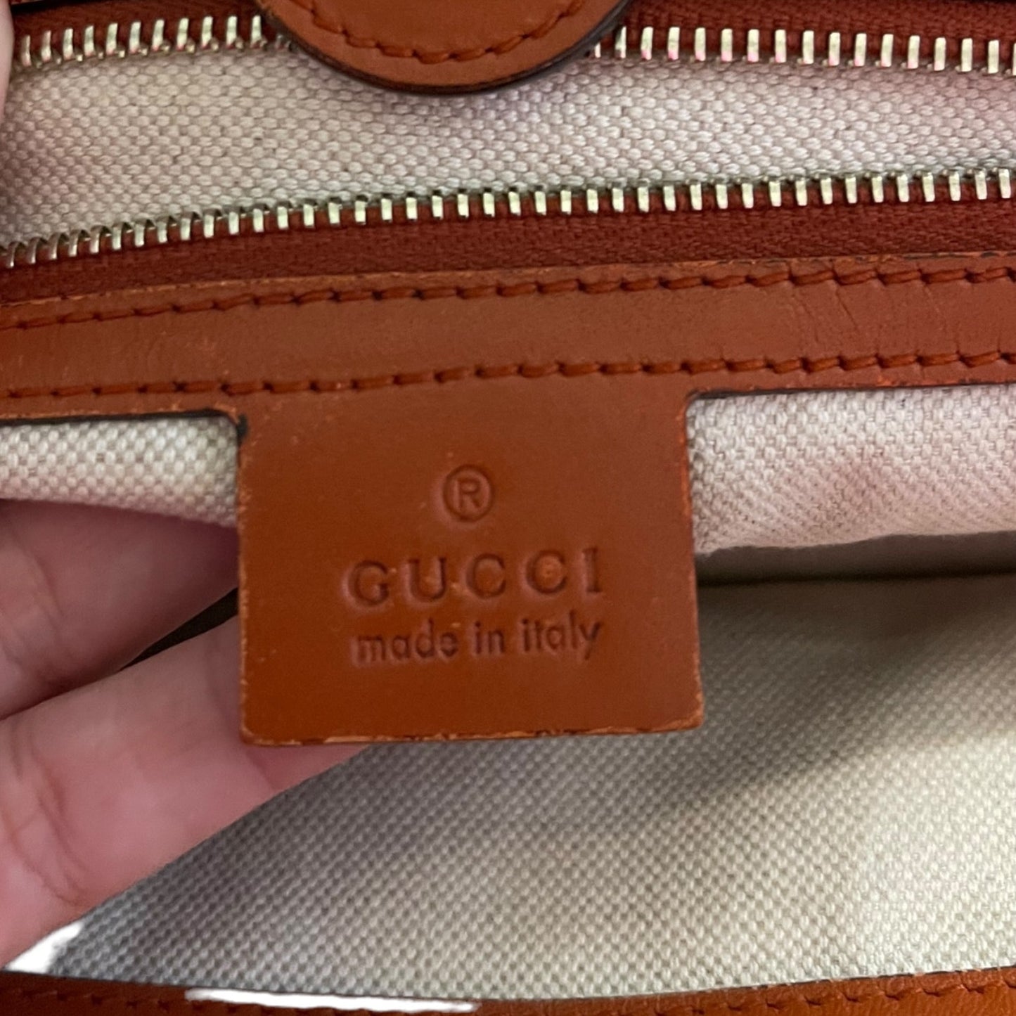 Close-up of a Gucci tag with a brown leather label.
