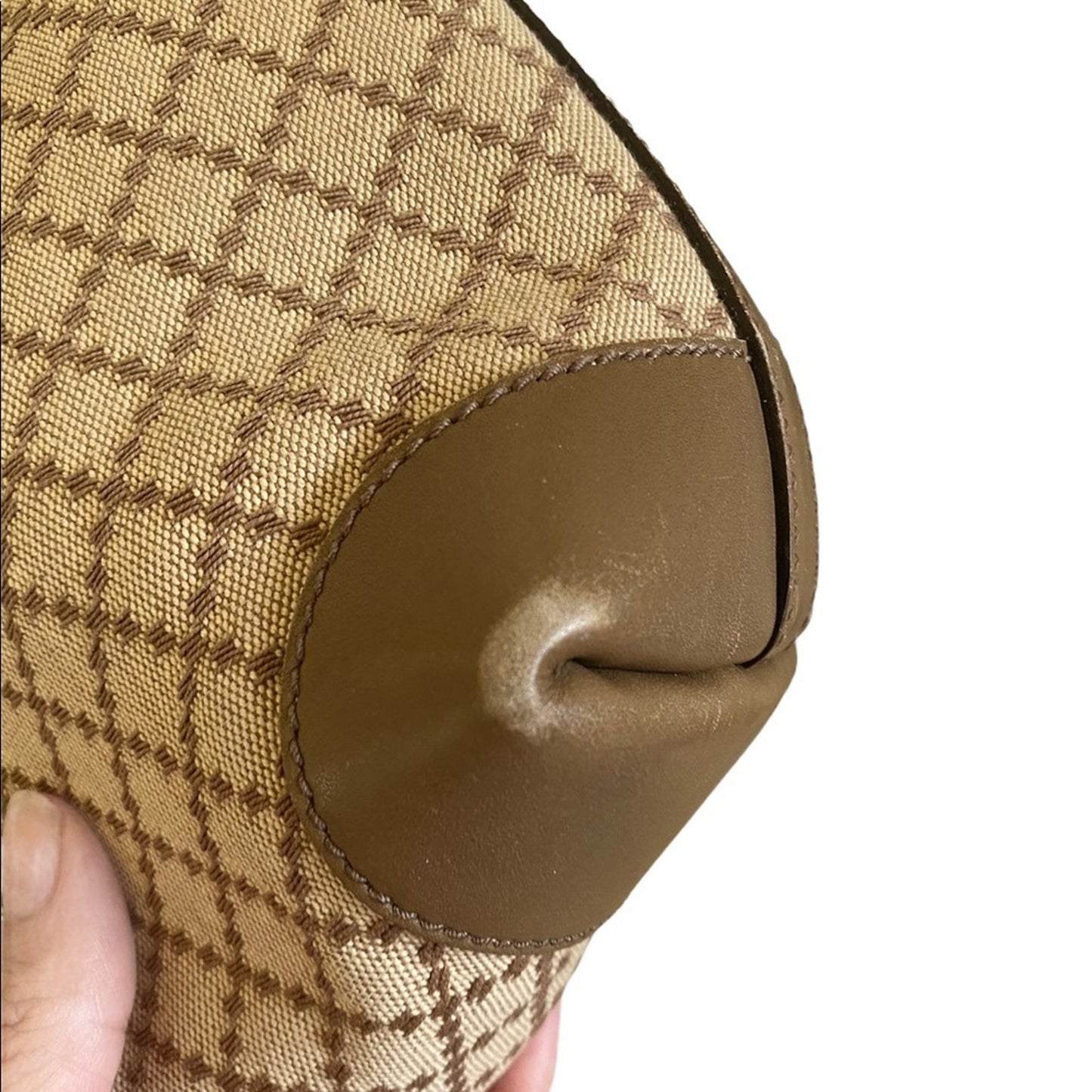 Close-up of a corner of brown purse with a checkered pattern on a white background