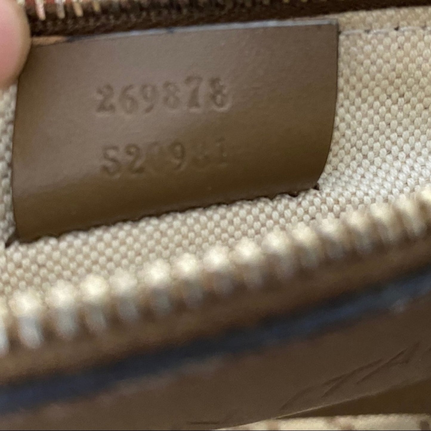Close-up of a leather tag with numbers on a product, likely a bag or wallet.