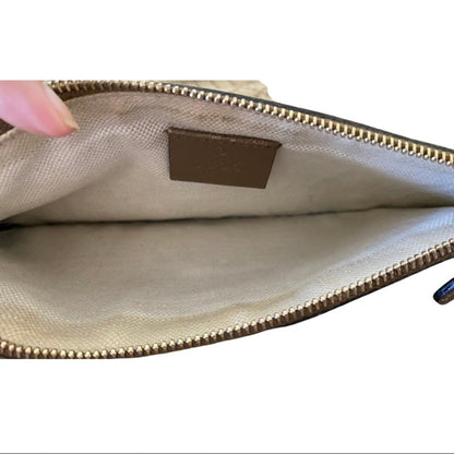 Close-up of a beige pouch with a gold zipper and visible brand logo on a white background.