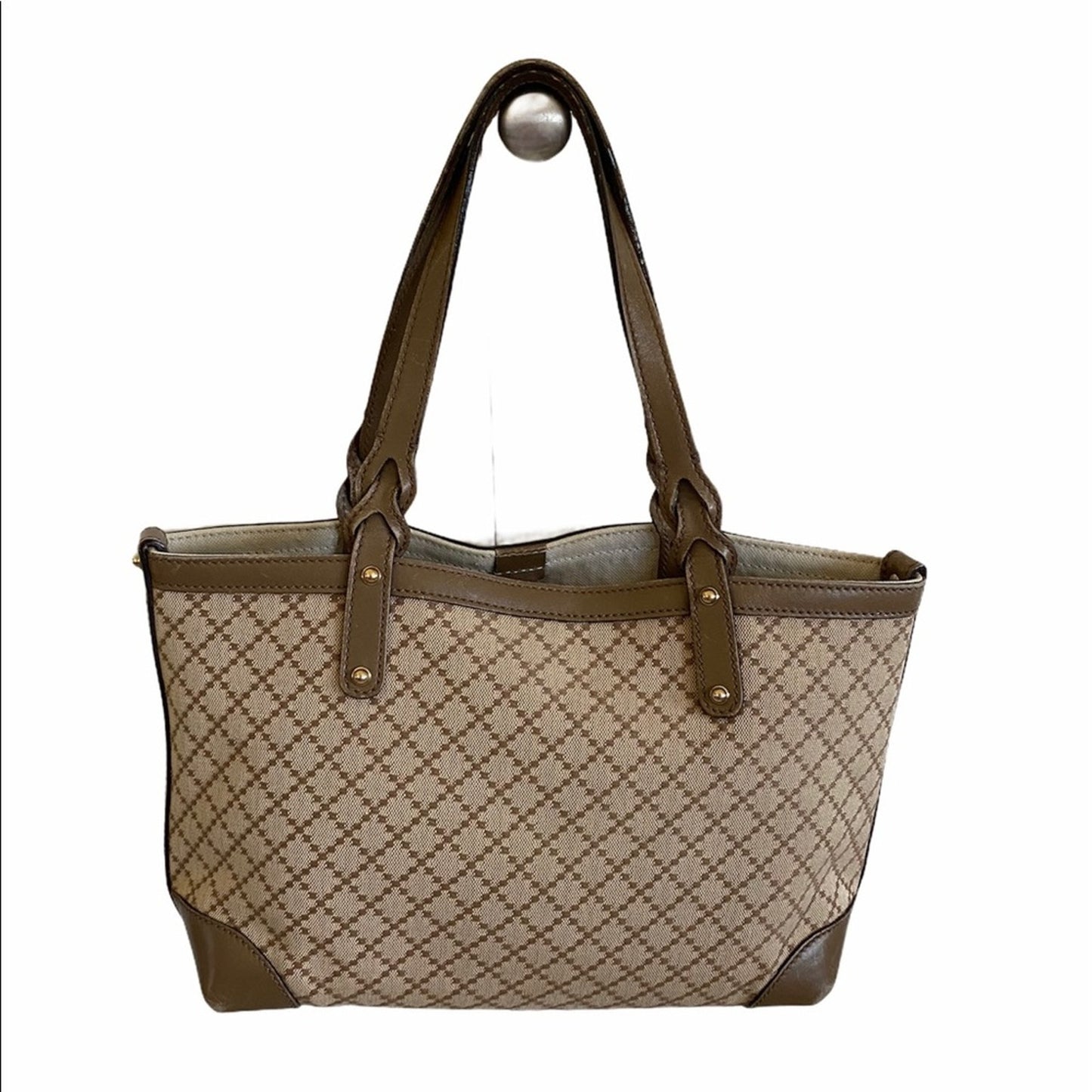 Back of Beige and brown patterned handbag with a matching handle on a white background