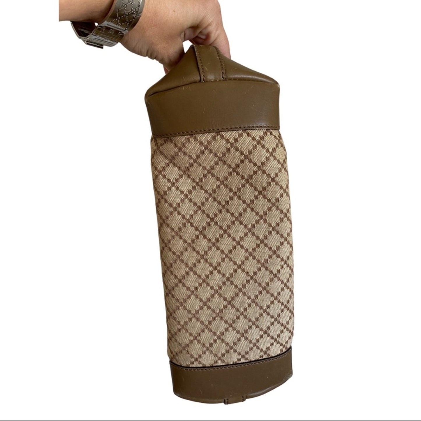 Patterned bottle holder with brown accents held by a hand on a white background