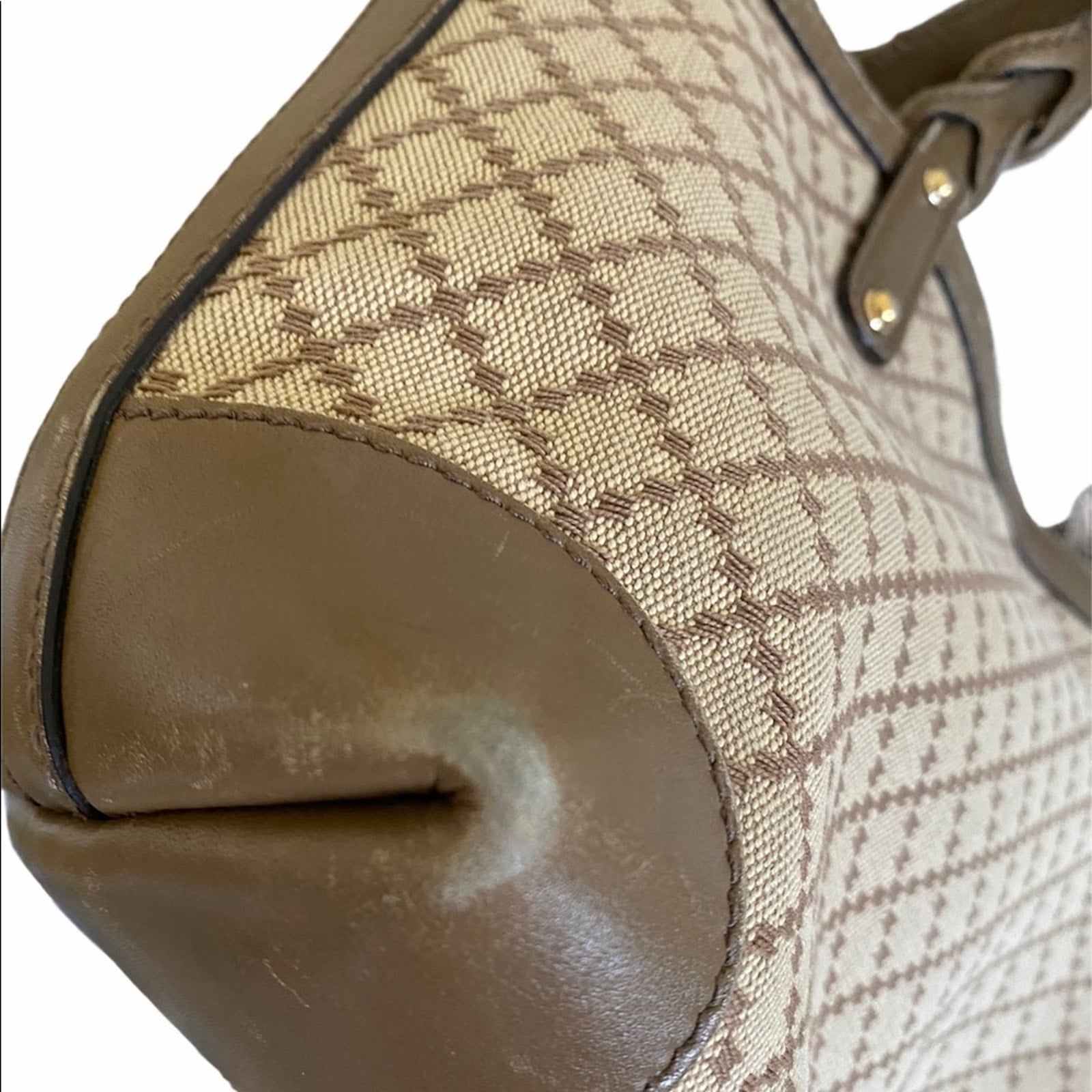 Close-up of corners of a brown handbag with patterned fabric and leather accents.