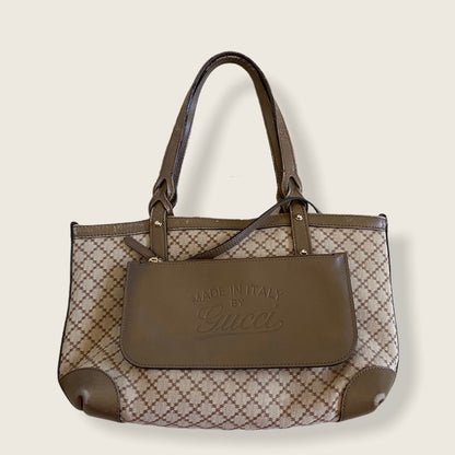 Brown handbag with patterned design and 'Made in Italy by Gucci' text on a beige background