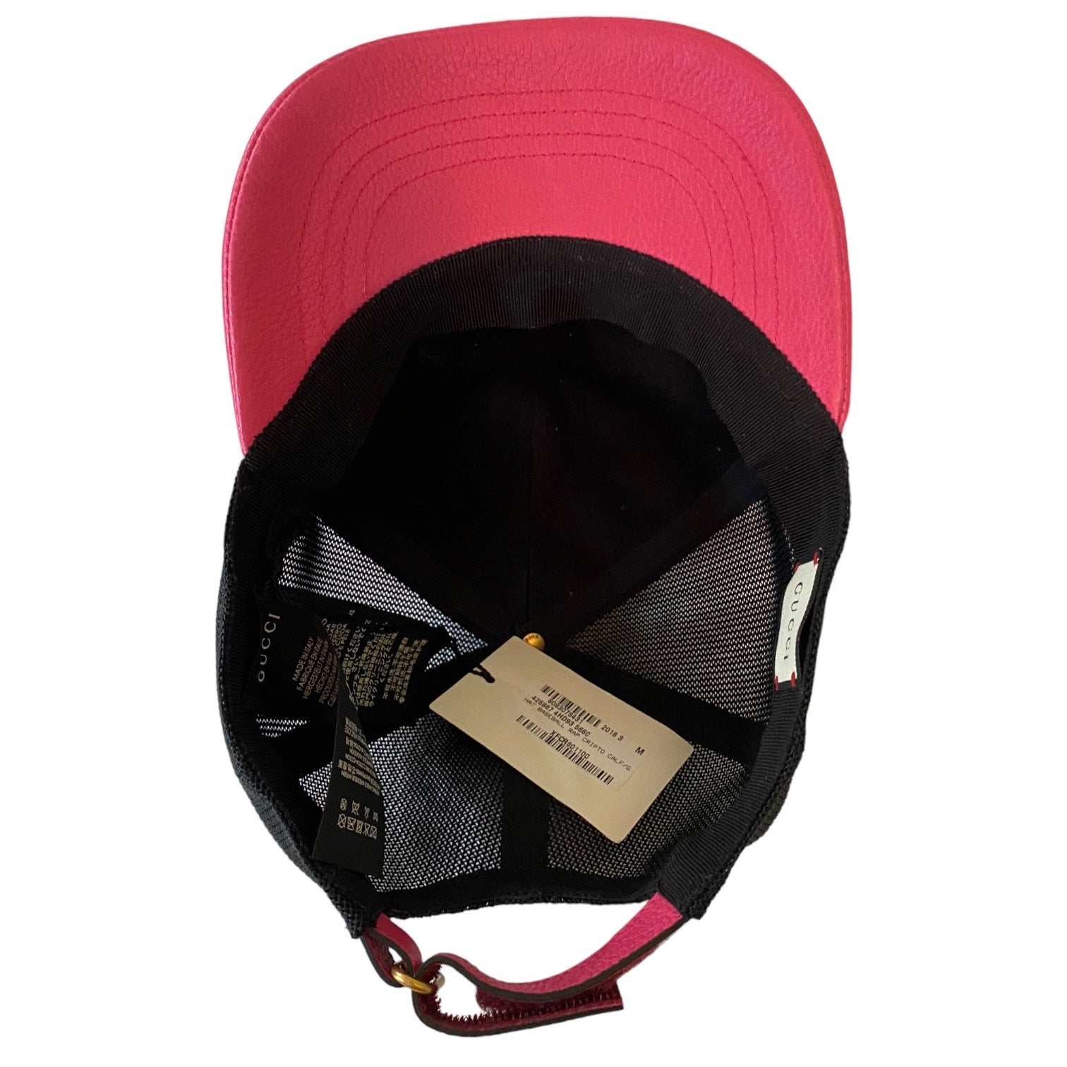 A Gucci trucker-style cap shown from the bottom, featuring a vibrant pink crown and a black mesh back, with a  hangtag and pink leather strap visible.