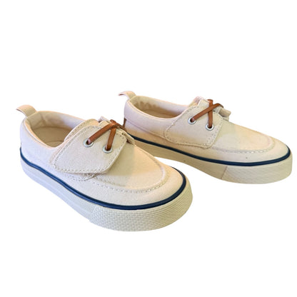 Front side of off white boat shoes with brown laces on a white background