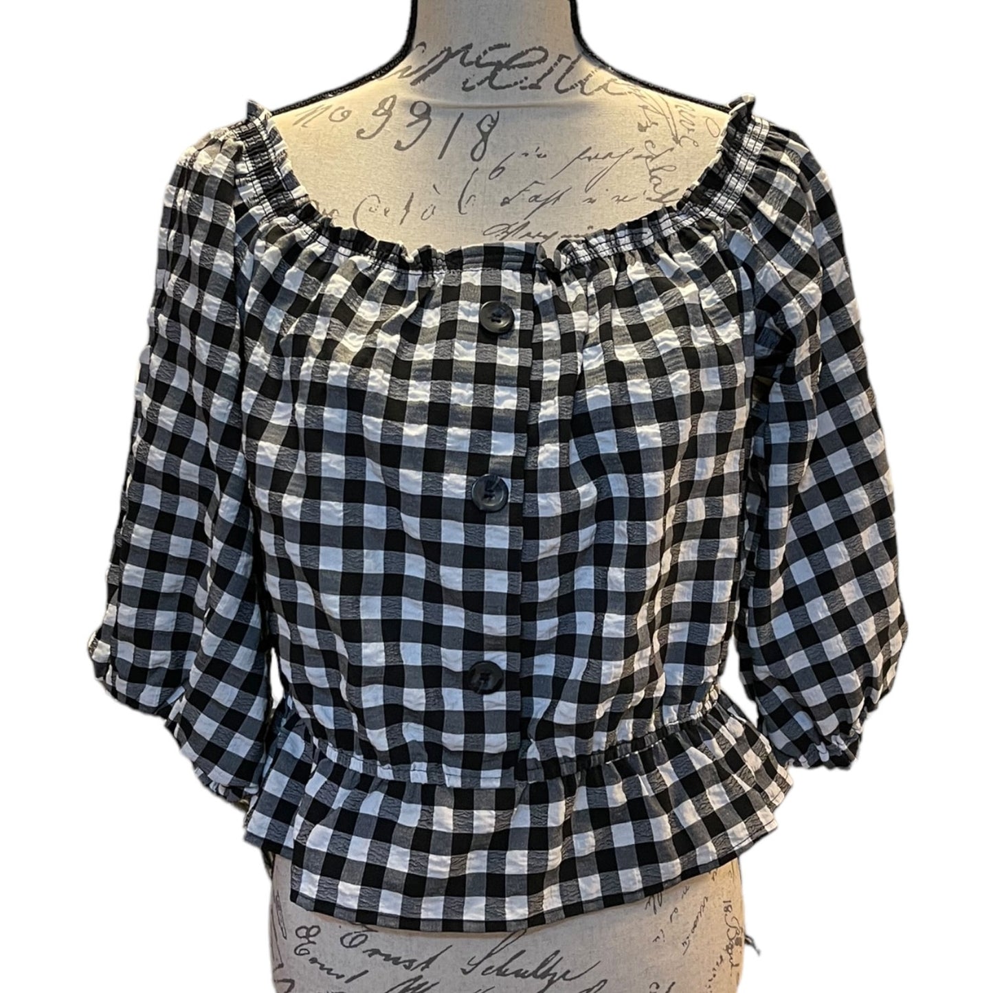 A black and white gingham blouse displayed on a vintage-style mannequin torso against a plain white background.