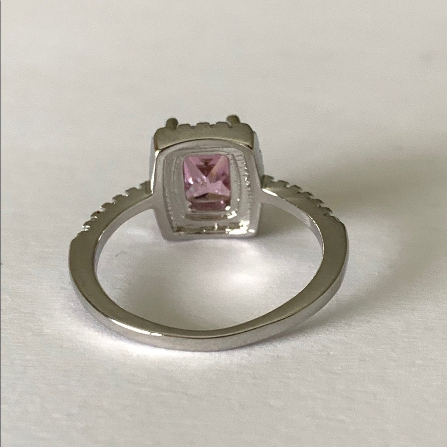 Back of Silver ring with a pink gemstone on a white background