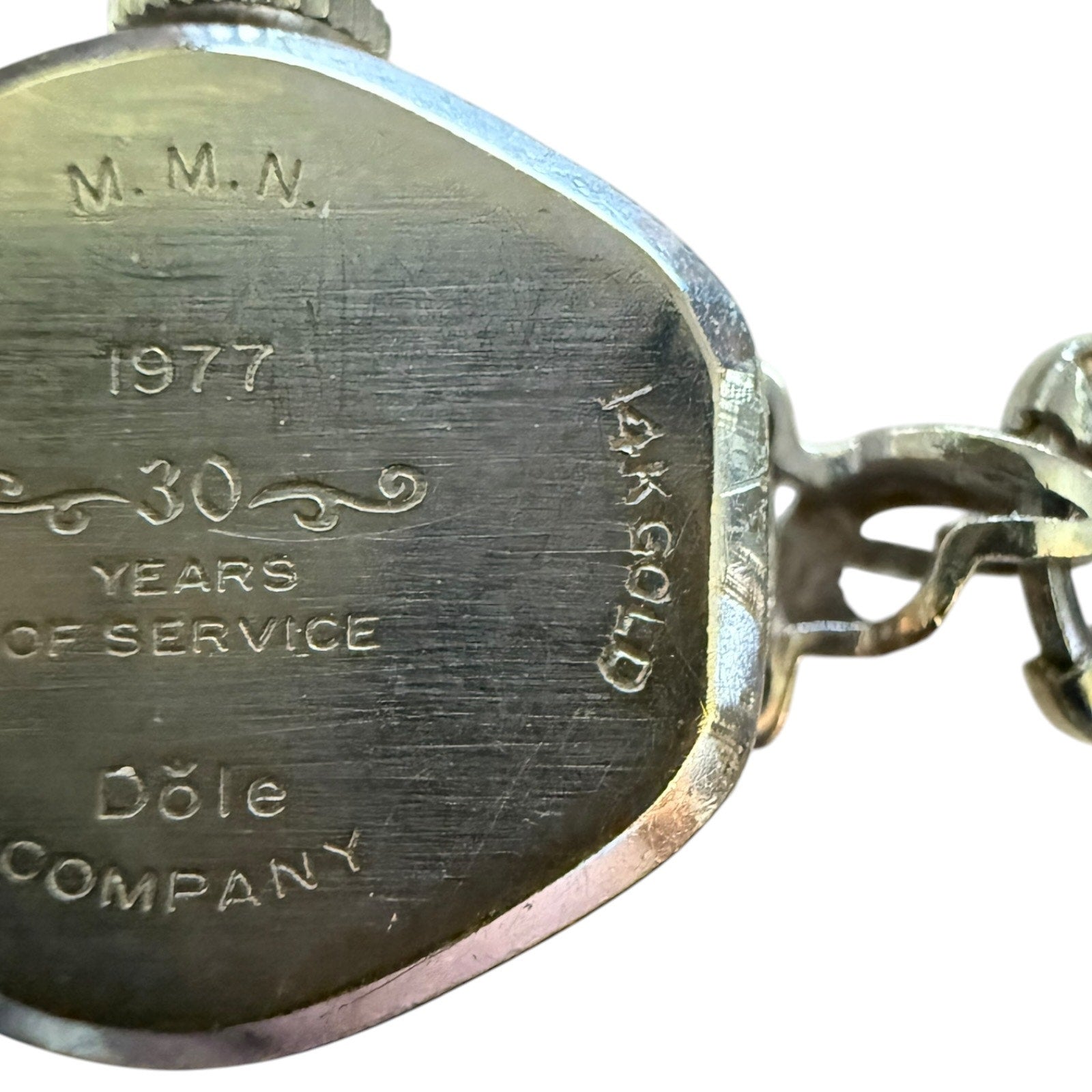 Close-up of a white gold watch with engraved text on a white background